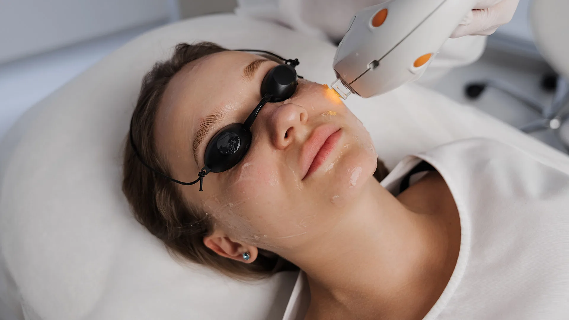 Woman receiving a light-based skin treatment with protective eyewear