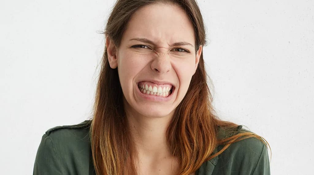 Woman gritting her teeth with gums showing, illustrating excess gum display when smiling