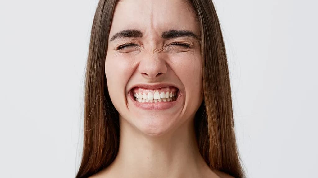 Young woman grinning widely with her upper gums showing, the pattern Botox for gummy smile corrects
