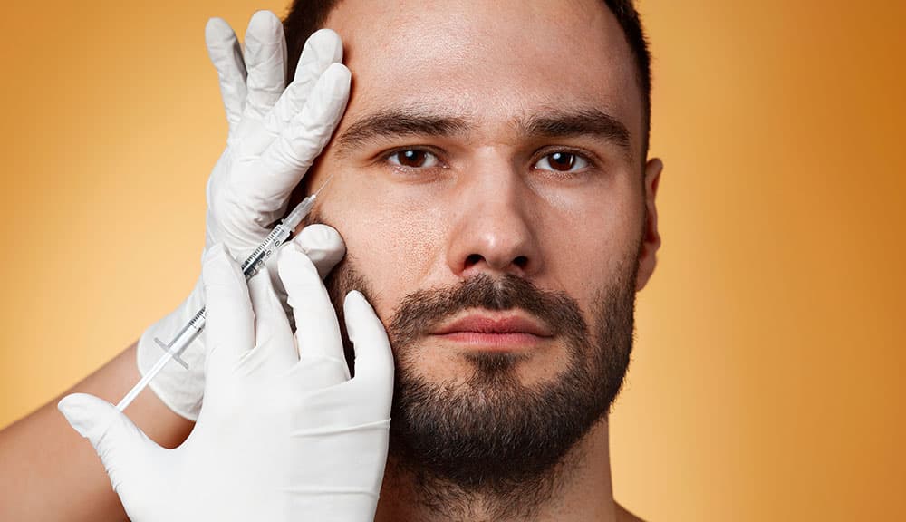 Man receiving a Botox injection near the crow's feet from a gloved provider