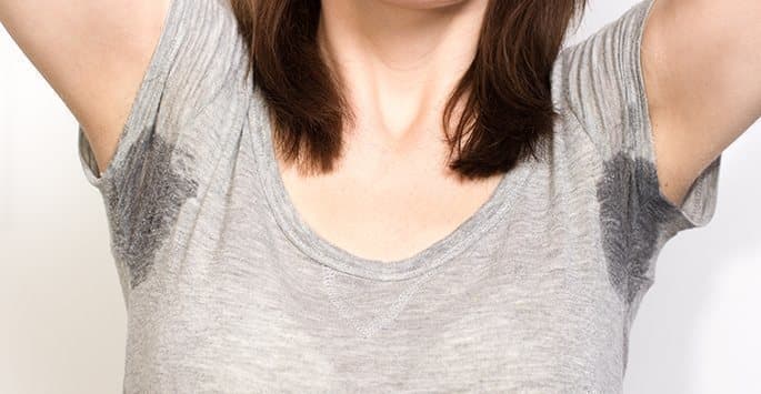 Woman with underarm sweat marks on her shirt from hyperhidrosis