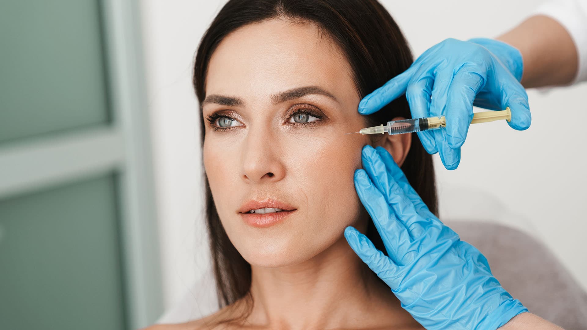 Woman receiving a Botox injection near the crow's feet from a gloved provider