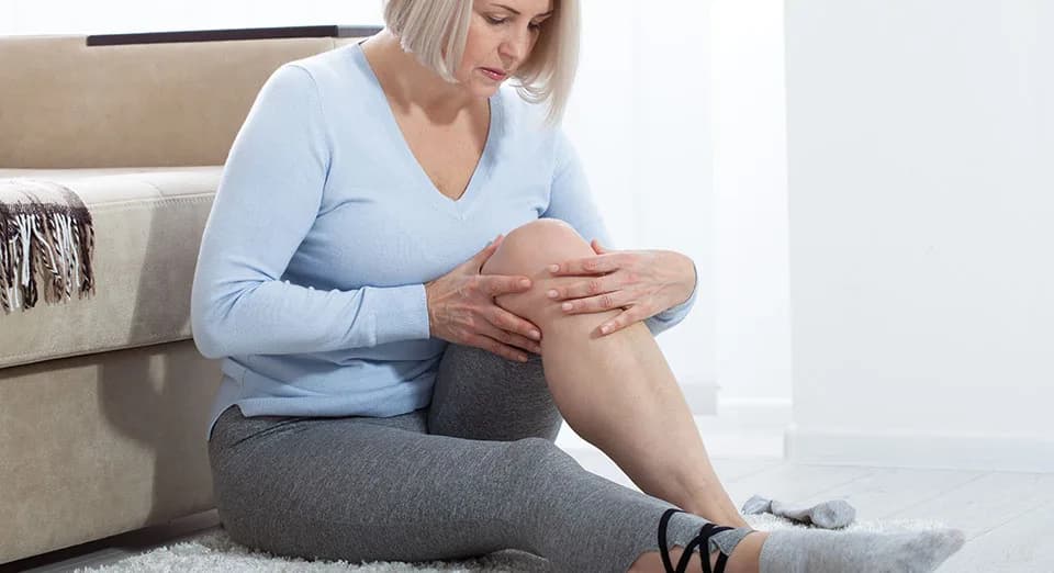 Woman holding her knee, the kind of persistent knee pain Emsculpt NEO strengthening can help