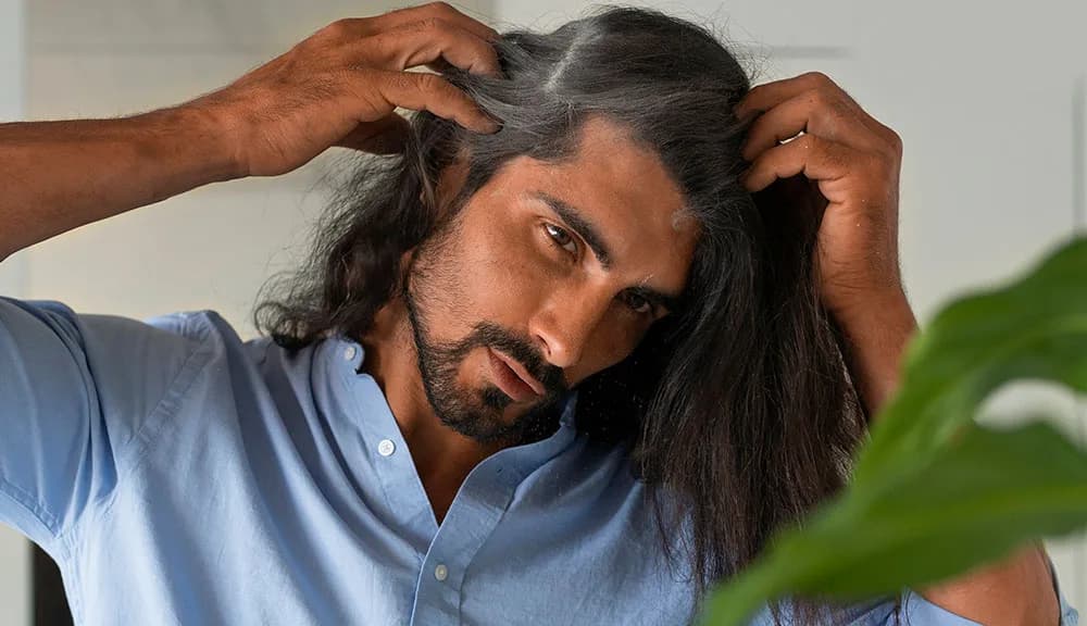 Man examining thinning hair at his part line