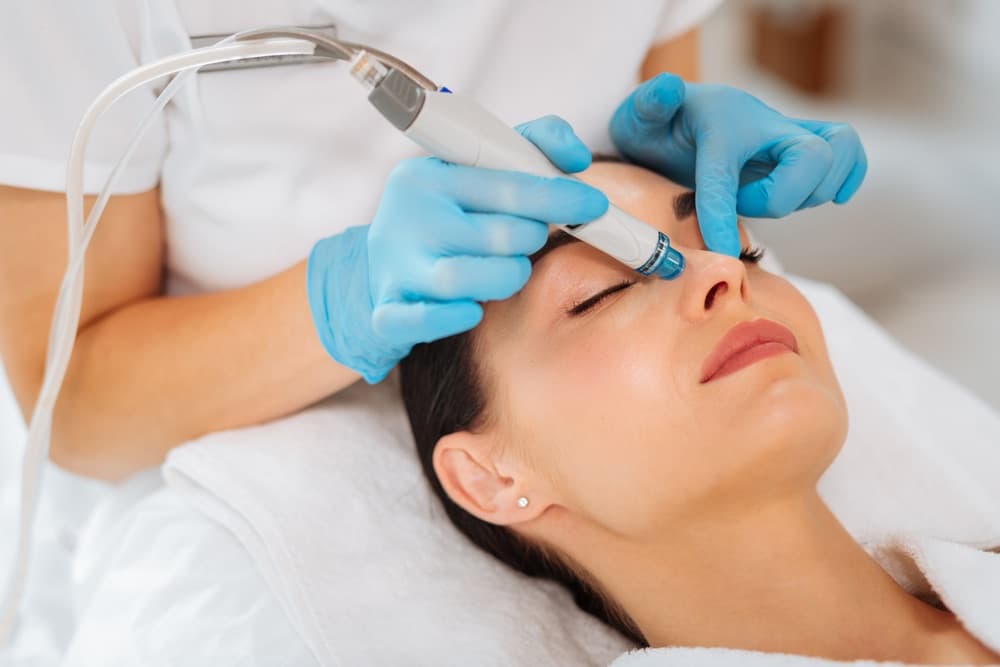 HydraFacial wand gliding across a woman's face during the extraction and hydration step