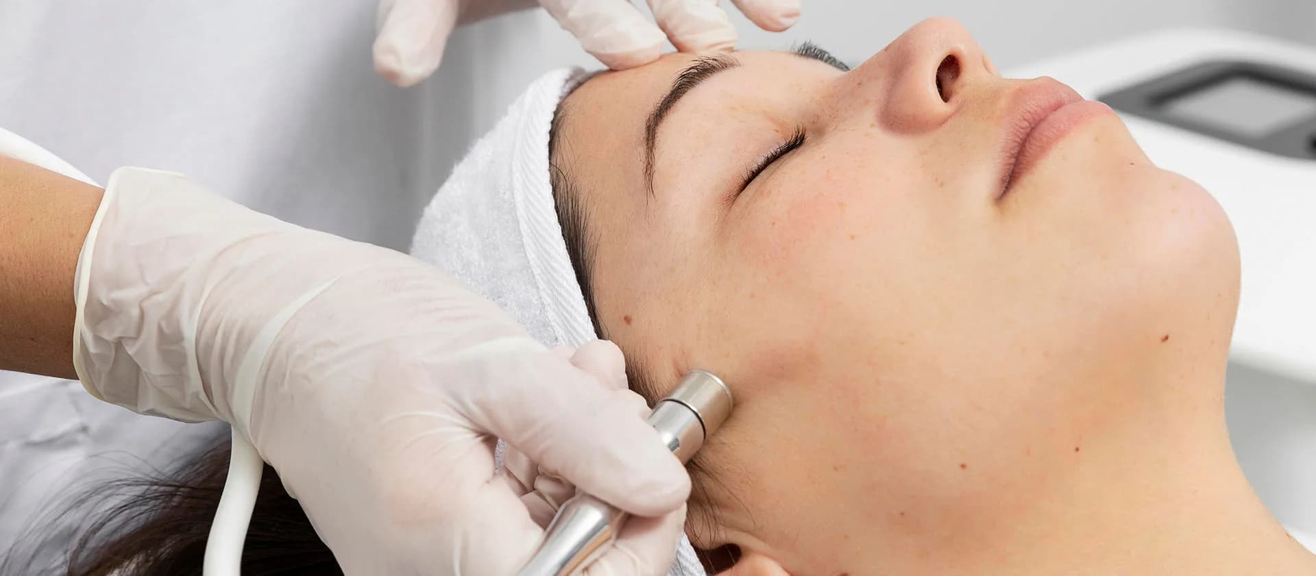 Technician gliding a microdermabrasion wand along a patient's jawline