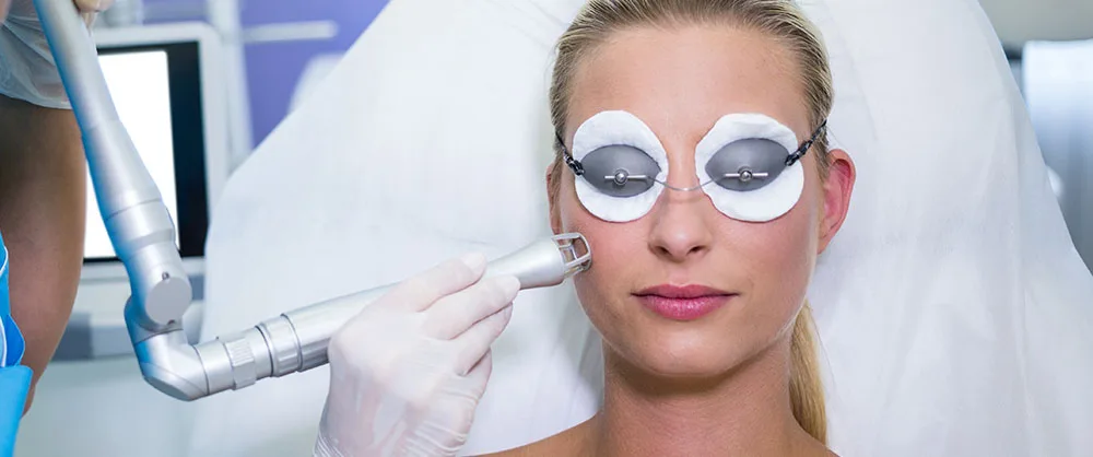 Patient with protective eye shields receiving a laser treatment on the cheek