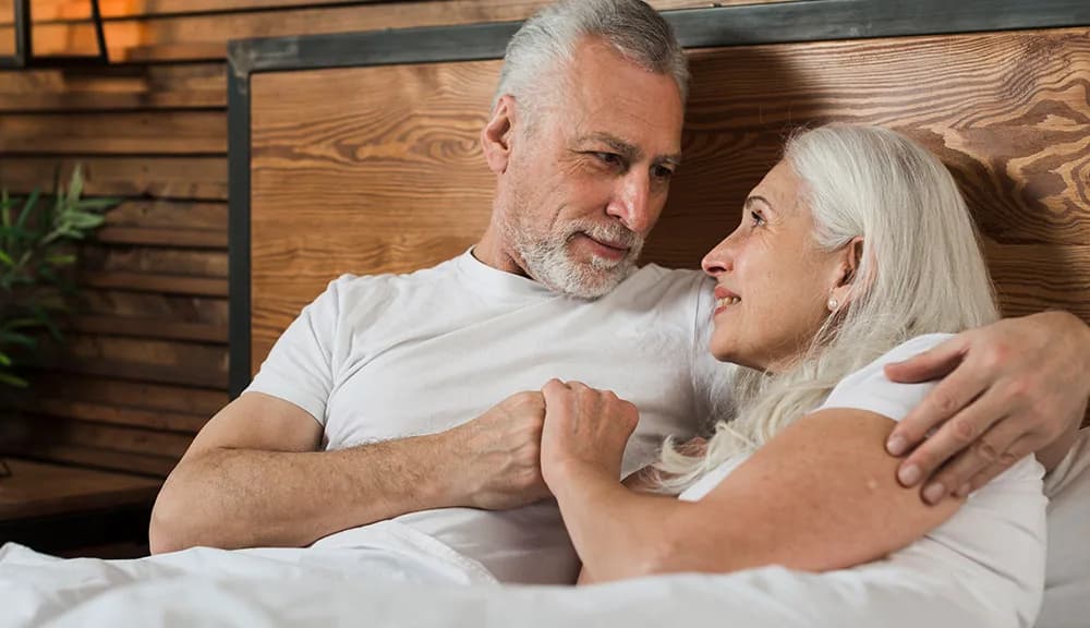 Older couple lying in bed gazing warmly at each other