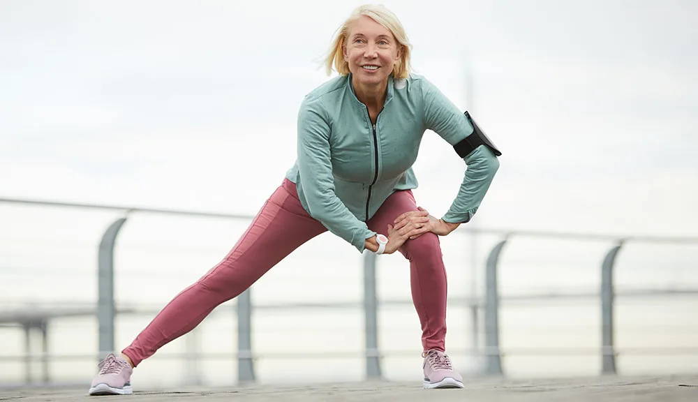 Active mature woman stretching outdoors before exercise