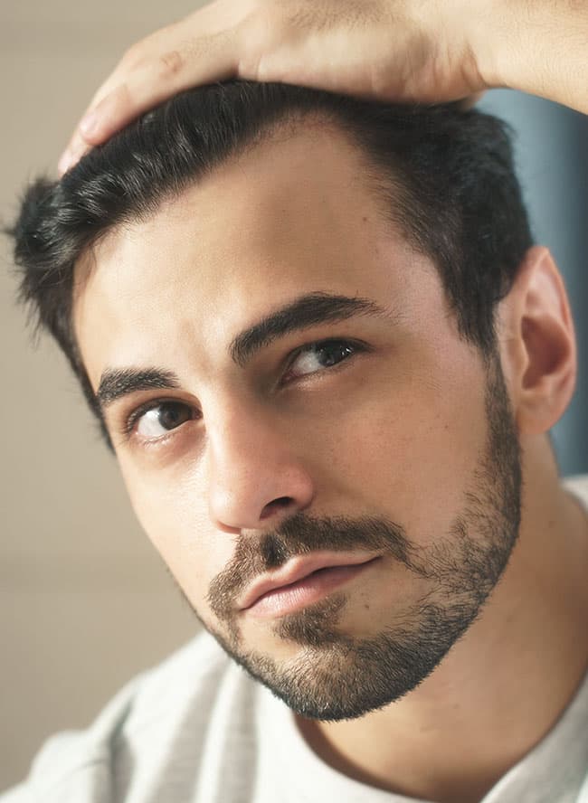 Man checking his hairline with his hand resting on his hair