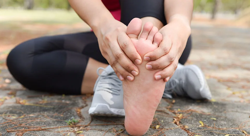 Woman in athletic wear massaging the sole of her foot from heel pain